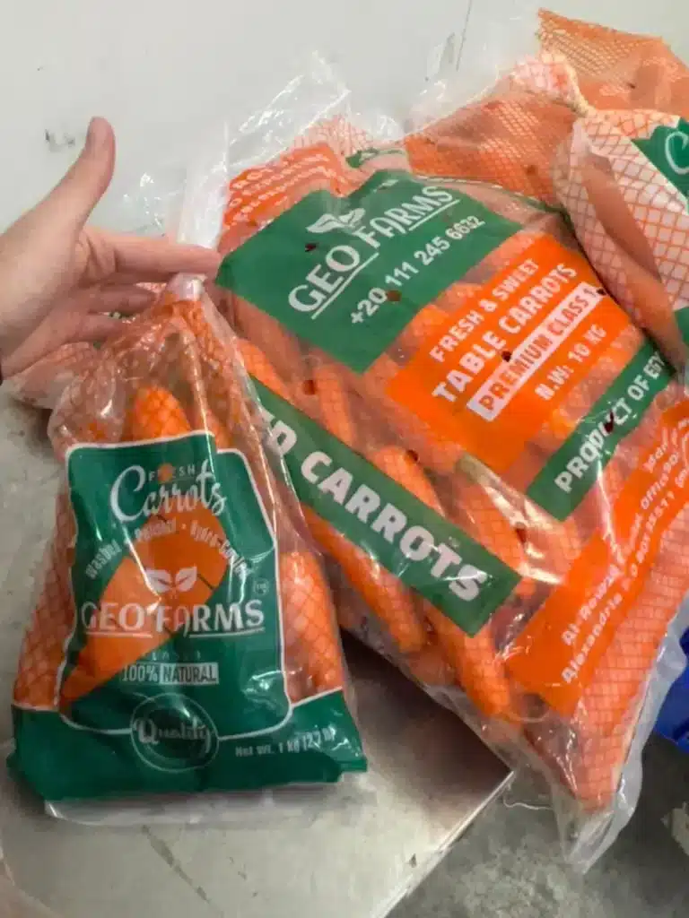 Side-by-side comparison of GEO FARMS carrot packaging: a 1kg retail poly bag and a 10kg bulk wholesale bag of fresh, premium Class 1 Egyptian carrots.